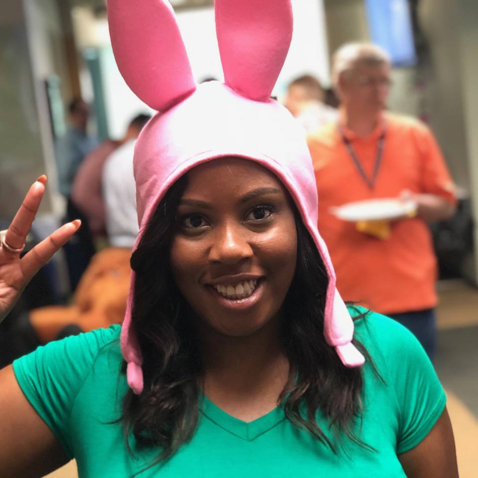 Woman holding up a peace sign, wearing pink bunny ears